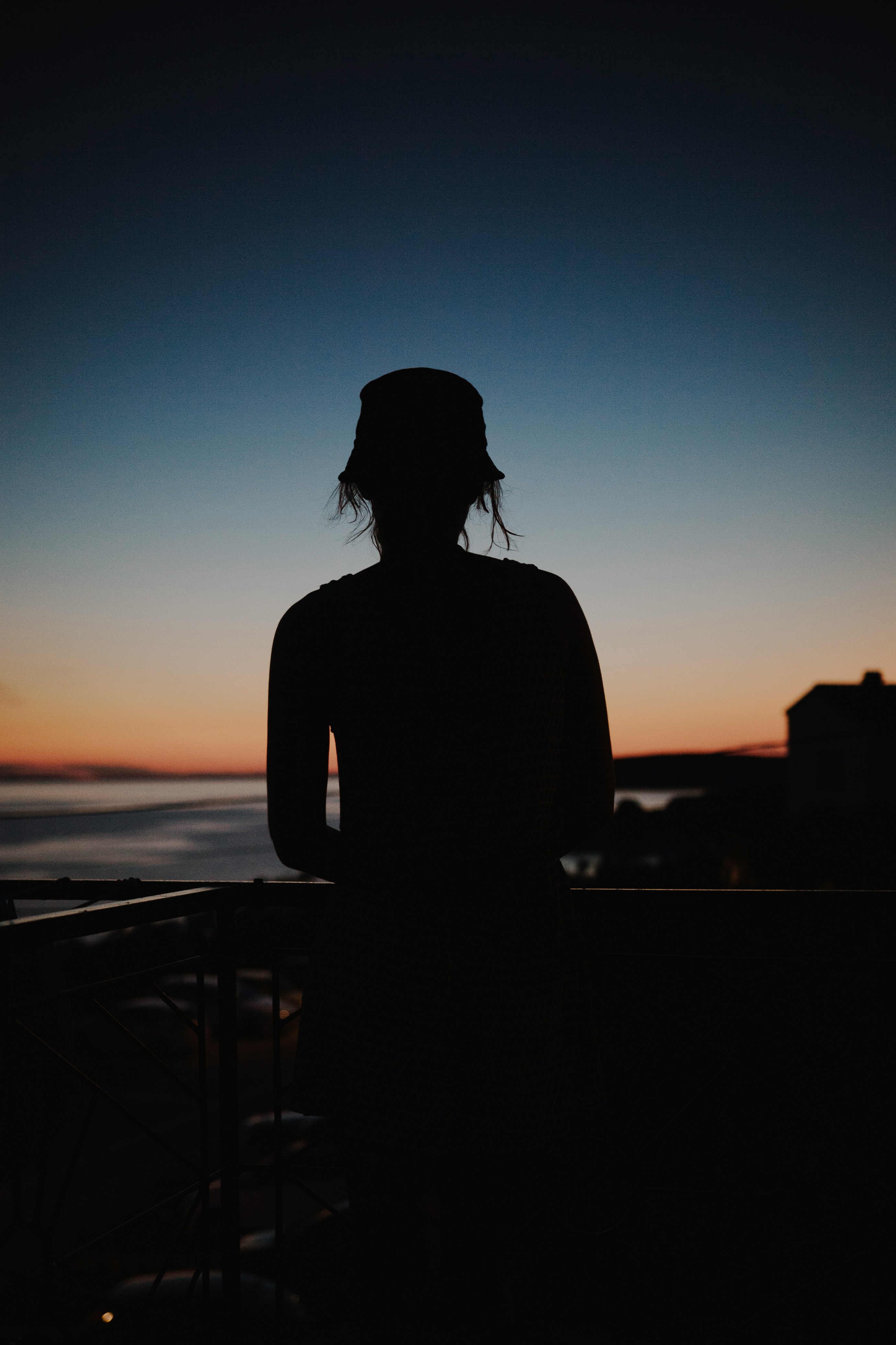 silhouette of woman standing near railings during sunset